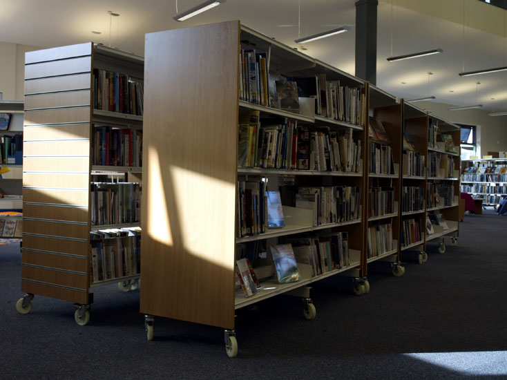 Library bookshelves arranged to form a narrow corridor.